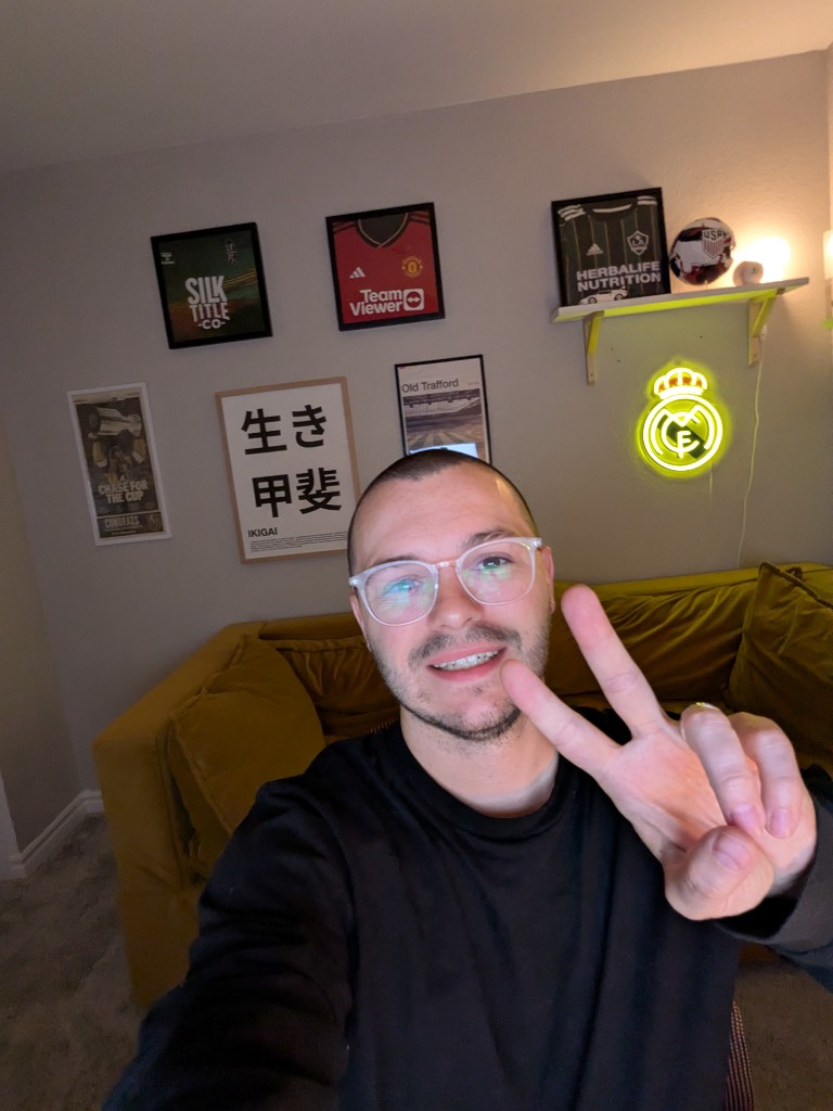 Jacob Olenick smiling in his home office with soccer memorabilia and a peace sign